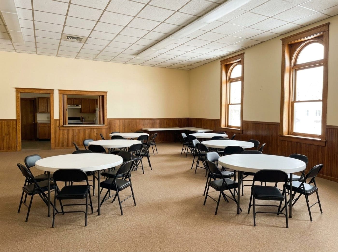 A spotless community hall set with round tables before an event